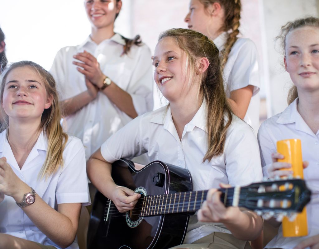 New grade 8 high school students, playing music together, with a girl playing a guitar in the middle
