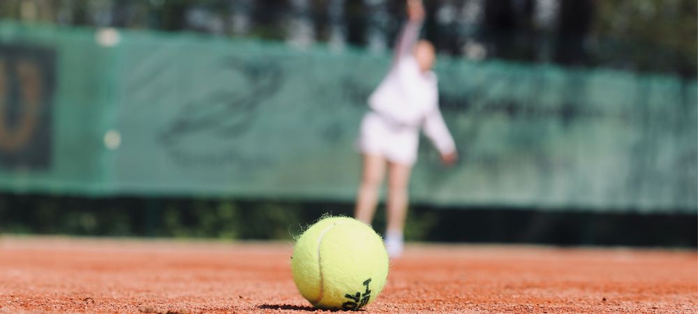 Closeup view of a tennis ball and a player balancing schoolwork and sports