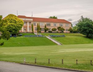 a new school for students switching schools, with green grass and a prestigious looking building.